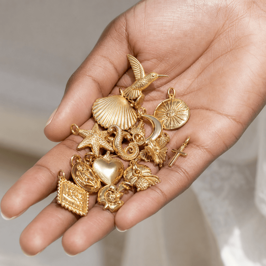 An array of solid gold charms and pendants held in hand.
