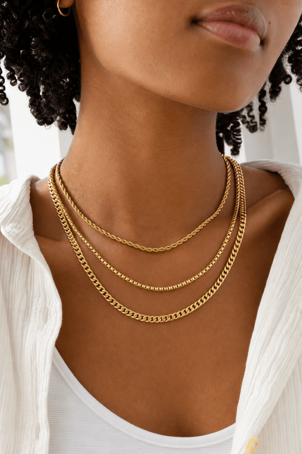 Person wearing layered solid gold necklaces.