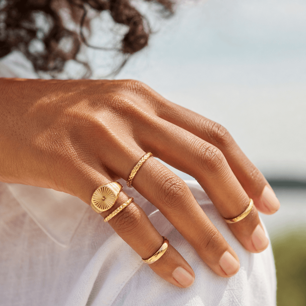 Solid gold rings worn across a hand.