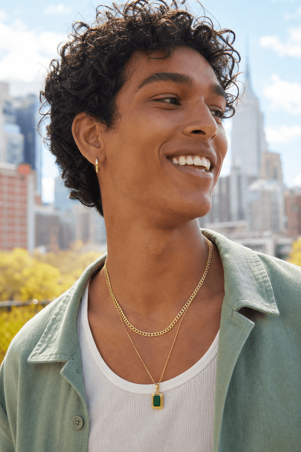 Person outdoors wearing solid gold chains and a pendant in soft NYC light.